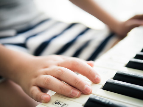 Boy playing keyboard piano near window at home.