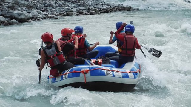 Raft boat with group of people goes into the wild water