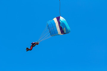 Skydiver and parachute on the blue sky background