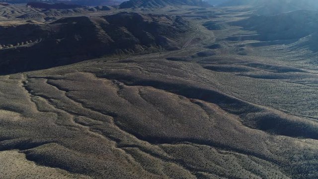 An aerial closing in on a road leading through the valley between captivating mountains