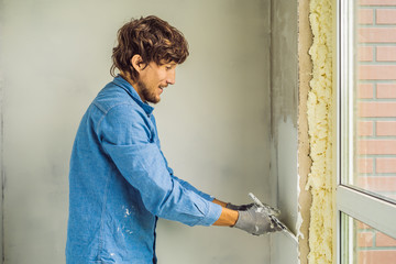master is applying white putty on a wall and smearing by putty knife in a room of renovating house...
