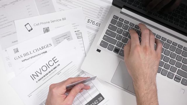 Paying bills using a credit card and a laptop computer. Online utility bills payment concept.