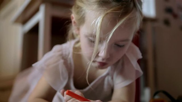 young blondie girl close up shot of her face while drawing with red pen