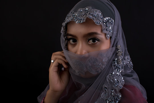 Portrait of muslim woman looking at camera over black background.