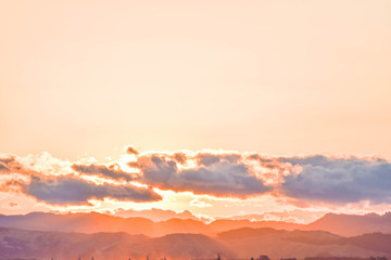 A pale peach colored and calm sunset floats above the countryside in Gisborne, New Zealand.