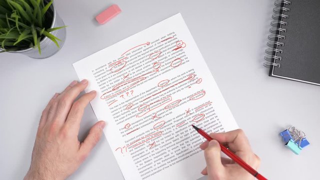Teacher correcting an exam or homework with a red marker pointing out all the errors in the text.