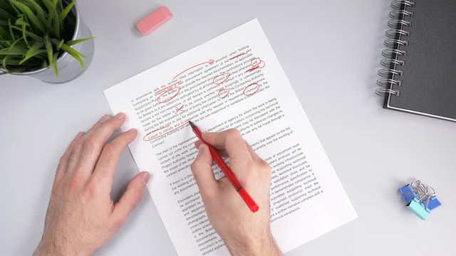 Teacher correcting an exam or homework with a red marker pointing out all the errors in the text.