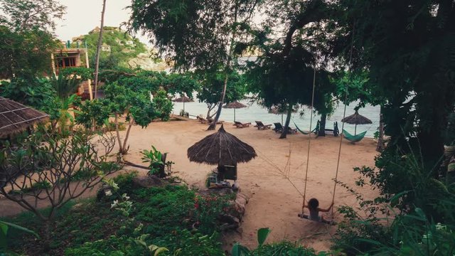 Cinemagraph of a young woman using a swing on a beach on the island Koh Tao in Thailand.