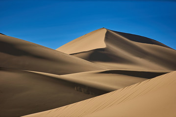 Sand dunes in the desert , warm dry sand under blue sky