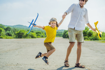 Happy father and son playing with toy airplane against old runway background. Traveling with kids concept