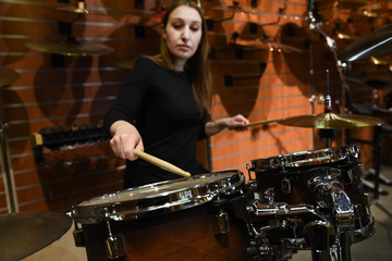 Professional drum set closeup. Beautiful young woman drummer with drumsticks playing drums and...