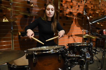 Professional drum set closeup. Beautiful young woman drummer with drumsticks playing drums and cymbals, on the live music rock concert or in recording studio   