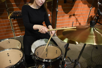 Professional drum set closeup. Beautiful young woman drummer with drumsticks playing drums and cymbals, on the live music rock concert or in recording studio   