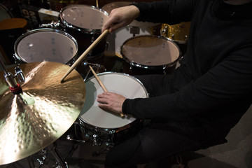 Professional drum set closeup. Man drummer with drumsticks playing drums and cymbals, on the live music rock concert or in recording studio   
