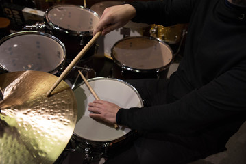 Professional drum set closeup. Man drummer with drumsticks playing drums and cymbals, on the live music rock concert or in recording studio   