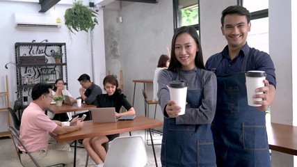 Baristas showing a cup of coffee at coffee shop and another customers.