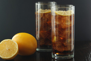 Glasses with cuba libre cocktail or cola with ice or cold tea with lemon	