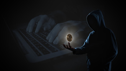 Golden Bitcoin floating above of hacker's hand in dark on hacker hacking with computer laptop...