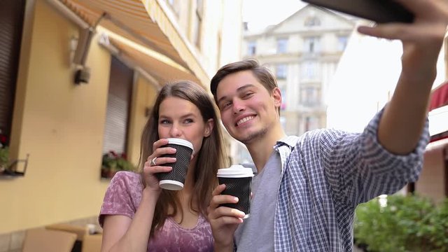 Couple Making Photo On Phone And Drinking Coffee At Street