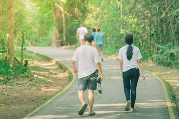 Obraz premium Back view of people walking on the hiking trail in the woods to
