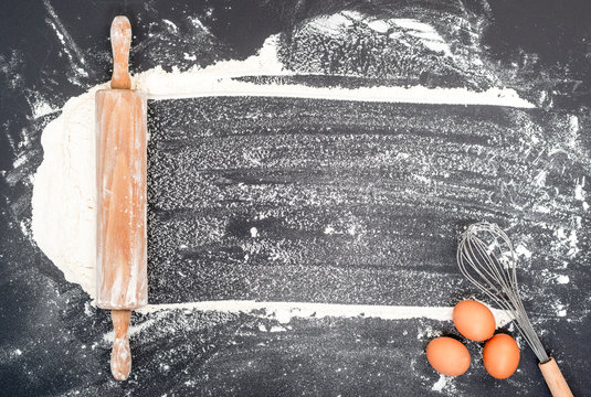 Home baking background with rolling pin flour and eggs on black background