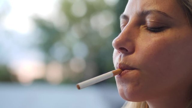 Slow motion profile close-up of a woman lighting a cigarette and smoking
