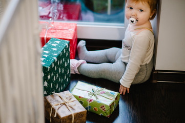 Portrait of a little girl sitting near gifts the holiday. Festive birthday concept. Happy baby in the photo. infant. International Women's Day, eighth of March. merry Christmas, happy holidays.