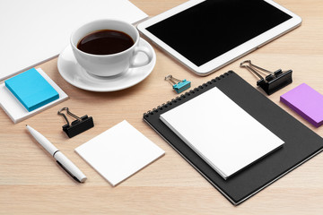 Digital tablet with notepad, supplies and coffee cup on desktop.