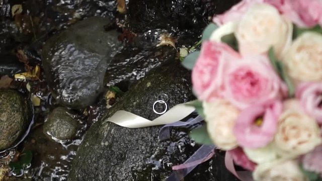 Wedding Bouquet On The Stone. Rings near rivulet