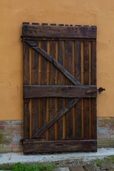 Wooden gate and orange wall with bricks 