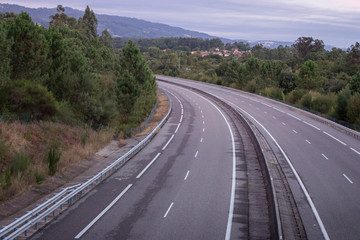 Wide empty highway with curve in the morning. Travel and destination background. Free asphalt road with mountain background. Motion and speed concept. Trip and journey concept. Driving concept.