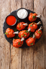 Delicious Deep frying Lollipops chicken wings with sauces close-up on a slate board. Vertical top view
