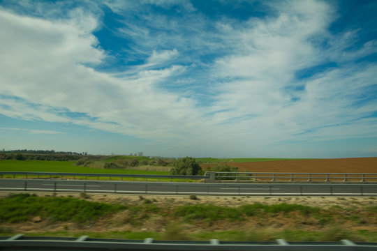 Green feilds and highway mooving cars veiw from side. The road along fields and forests