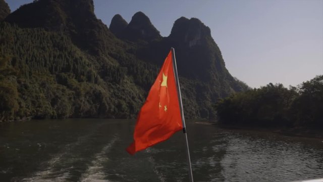 Chinese flag on boat with a beautiful view of mountains from Guilin, Mainland China on the Li River.