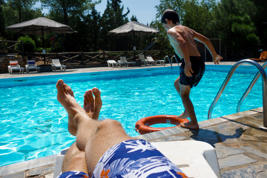 Relaxed parent with sun jumping into swimming pool - Powered by Adobe