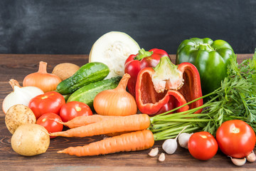 Vegetables on wooden background. Carrot, red pepper, cucumbers, tomatoes, garlic, potatoes and onions.