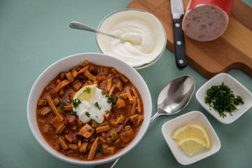 Typische DDR Soljanka Suppe in Schale mit Schmand und Zitrone