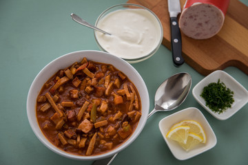 Typische DDR Soljanka Suppe in Schale mit Schmand und Zitrone