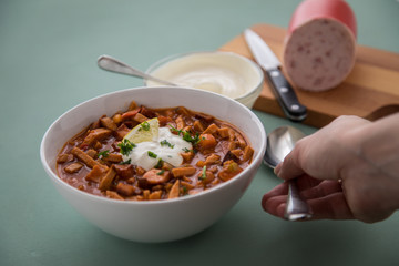 Frau isst typische DDR Soljanka Suppe in Schale mit Schmand und Zitrone