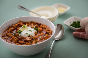 Frau isst typische DDR Soljanka Suppe in Schale mit Schmand und Zitrone