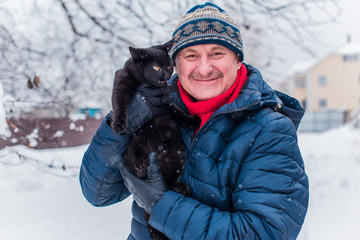 Fototapeta na wymiar Senior man on a walk with black cat. Positive lifestyle and life after 50 -60 year. Good mood and holiday joyful with pet