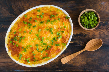 Fish casserole. Tilapia baked with potatoes, green peas and boiled eggs in bechamel sauce. White baking dish on wooden rustic table, spring onion. Top view, overhead. - 238864167