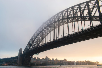 Sydney Harbour Bridge view under sunrise light and fog.
