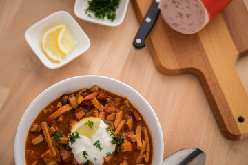 Typische DDR Soljanka Suppe in Schale mit Schmand und Zitrone