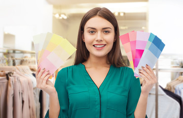 fashion, style and shopping concept - smiling young woman with color swatches or samples over...