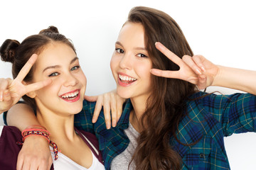 people, gesture and friendship concept - happy smiling pretty teenage girls hugging and showing peace hand sign over white background