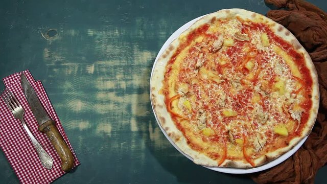 Pizza with chicken, vegetables and pineapple. Italian cuisine. View from above. Free space for text. On blue wooden background. Rotates.
