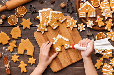 Woman decorating homemade gingerbread cookies, top view