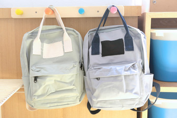 green and gray kid backpacks hanging on the wall