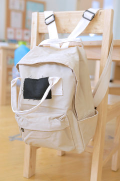 Beige Kid Backpack Hanging On A Chair